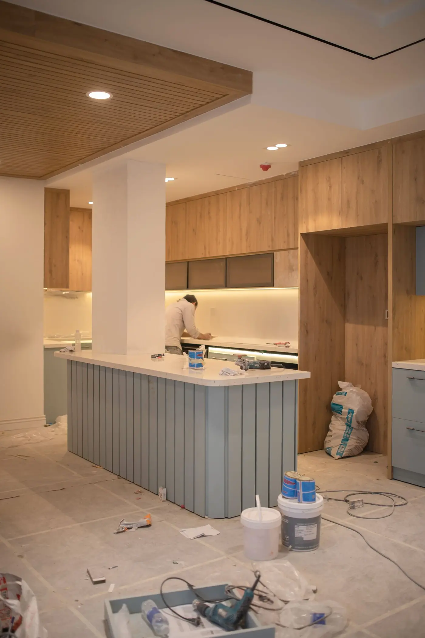 Cuisine lumineuse en cours de rénovation, meubles en bois posés et sol protégé